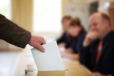 Eine Person wirft einen Stimmzettel in eine Wahlurne